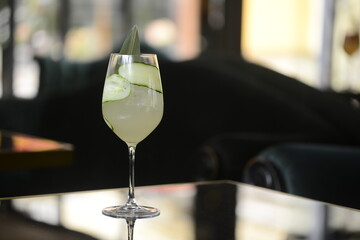 alcoholic cocktail with cucumber in a glass on a glossy surface
