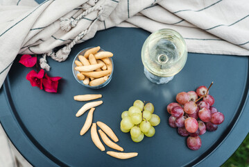 A glass of white wine with appetizers on the table.