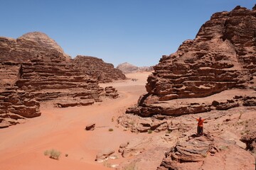 Amazing scenery of Wadi Rum desert with eroded rocks and red sand. Silhouette of standing woman...