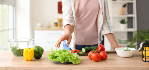 Young woman with fresh vegetables on table in kitchen