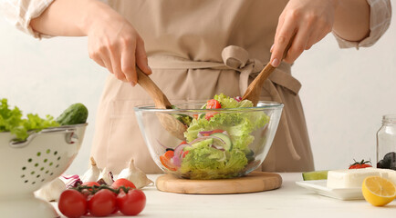 Obraz na płótnie Canvas Woman preparing tasty Greek salad in kitchen