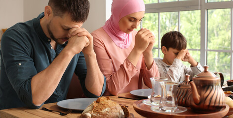 Muslim family praying together before breakfast. Celebration of Eid al-Fitr