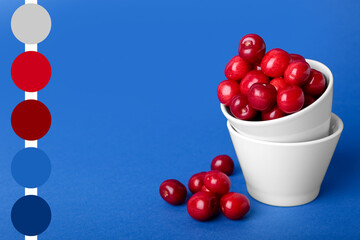 Bowls with sweet cherries on blue background