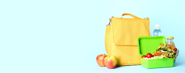 Child's bag and lunchbox with tasty food on light blue background with space for text