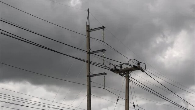 Time lapse of dramatic skies and black clouds with electric poles and wires. Dark grey storm clouds. Nature weather of dark sky.