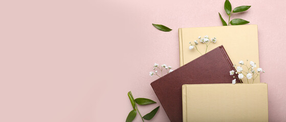 Books with floral decor on pink background with space for text