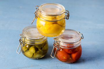 Homemade Pickles Canned Food Cucumbers Cherry Tomatoes and Small Yellow Squash on Blue Background Horizontal