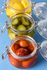 Homemade Pickles Canned Food Cucumbers Cherry Tomatoes and Small Yellow Squash on Blue Background Above Vertical