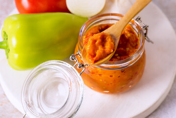 Preparation of Canned Lecho Canned Tomatoes Peppers Onion Garlic in a glass jar Above Horizontal