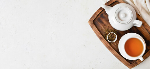 Teapot and cup of tasty hojicha green tea on light background with space for text