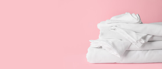 Stack of clean bed sheets on pink background with space for text