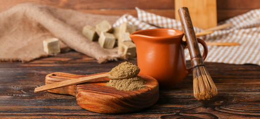 Board with hojicha powder, jug of milk and chasen on wooden background
