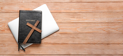 Holy Bible, laptop and cross on wooden background with space for text