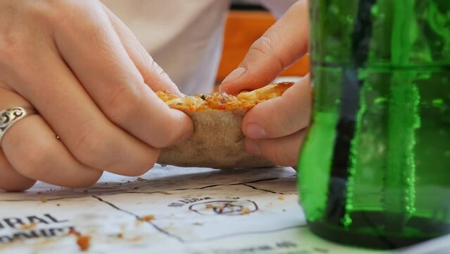 a woman eats a turkish pide with the fingers of her hand tears a slice of peda with cheese on a plate close-up. Lunch at a street Turkish restaurant in the open air.