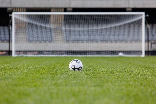Football ball on fresh green grass pitch. Soccer ball at big stadium