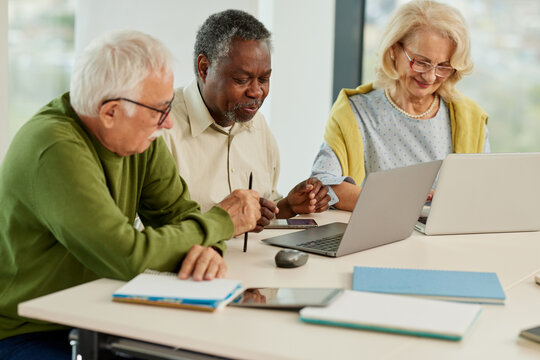 A Cheerful Multicultural Group Of Senior Students Is Doing An Assignment On Laptops In The Classroom.