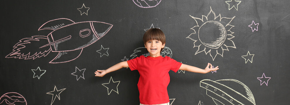 Happy little boy near blackboard with drawn space