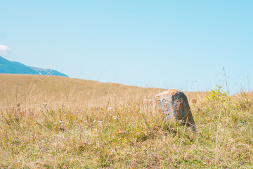 Concrete pole on the mountain hill. Border. Marker. Meadow. Point. Stop. Limit. Line. Way. Air....