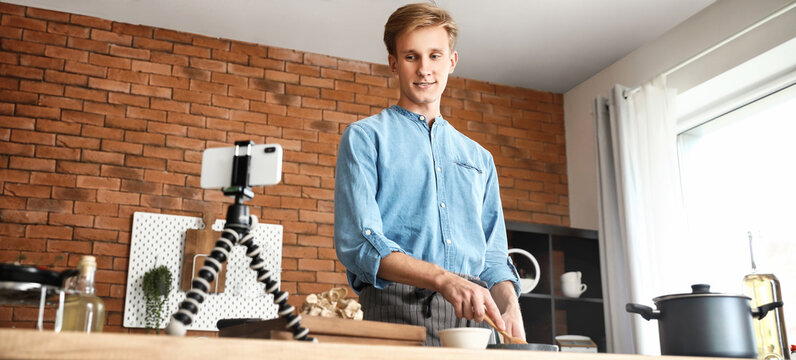 Young male blogger recording video while cooking in kitchen