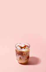 Glass of delicious cold brew coffee with milk on pink background