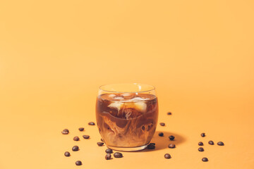 Glass of delicious cold brew and coffee beans on color background