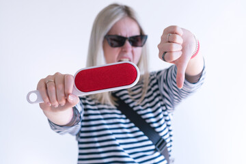 An unhappy woman holds a red electrostatic clothing brush and shows thumbs down on a white...