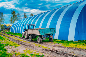 Blue tractor with trailer. Equipment for agriculture. Successful farming. Hangars on a large farm