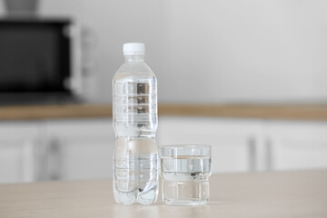 Plastic bottle and glass of water on kitchen table