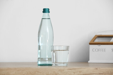 Bottle and glass of clean water on kitchen counter