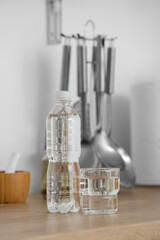 Plastic bottle and glass of clean water on kitchen counter