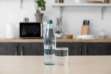 Bottle and glass of clean water on kitchen table