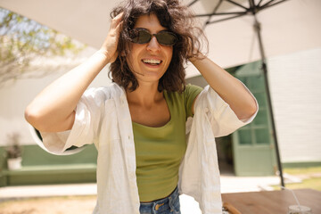 Happy young caucasian woman ruffled her hair smiling looking at camera outdoors. Brunette with bob...
