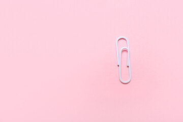 White paper clip on pink background