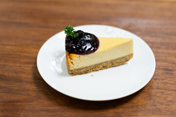 Piece of cheesecaket and blueberry sauce on white plate