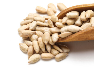 Closeup view of wooden scoop with peeled sunflower seeds on white background