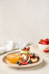 Delicious cottage cheese pancakes with berries and bowl with honey served on white table