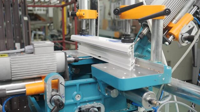 Plastic doors and windows manufacturing facility - machine processing PVC profile piece in factory production.