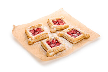 Parchment paper with strawberry puff pastries and sugar powder on white background