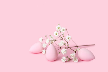 Makeup sponges and gypsophila flowers on pink background