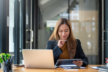 Obraz premium Young Asian businesswoman working happy in the office with laptop computer.