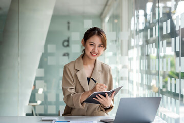 Young Asian businesswoman working happy in the office with laptop computer.