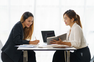 Two beautiful Asian businesswoman discussing financial paperwork and company account.