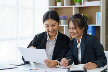 Two beautiful Asian businesswoman discussing financial paperwork and company account.