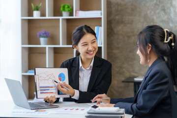 Two beautiful Asian businesswoman discussing financial paperwork and company account.