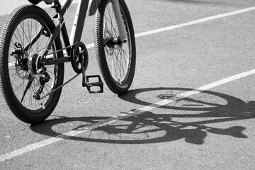 Fototapeta na wymiar An adult bike at sunset and a shadow on the road, black and white