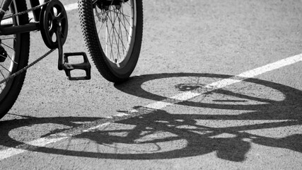 Fototapeta na wymiar An adult bike at sunset and a shadow on the stadium road, black and white