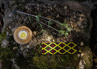 Shamanic paraphernalia a candle, a bracelet and a thorn lie on an old mossy slab, flat lay