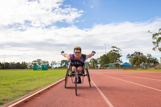 young man in a racing wheelchair demonstrating racing technique on track