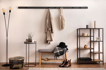 The stylish composition of cosy entryway with grey bench, black consola, hanger and lamp. Beige wall. Home decor. Template. - obrazy, fototapety, plakaty