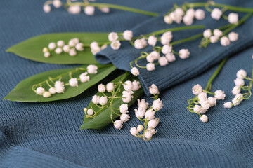 knitted sweater and a bouquet of fresh lilies of the valley. concept for dry cleaning and washing delicate clothes.